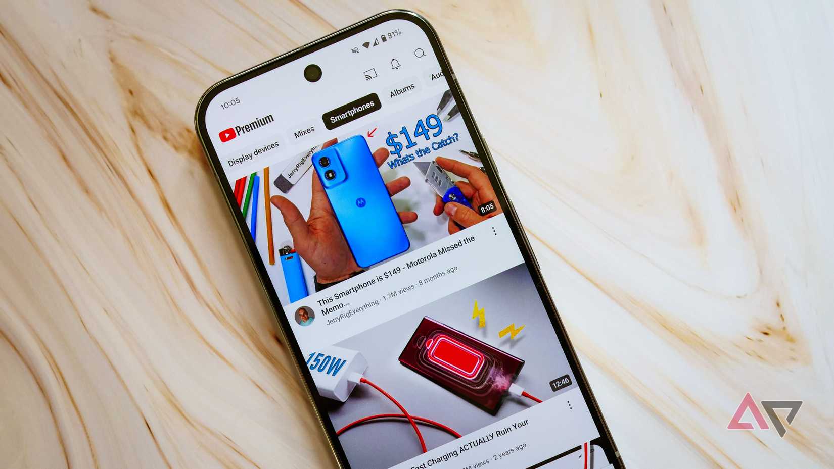 A phone with the YouTube Premium app sits atop an unfinished wood plank.