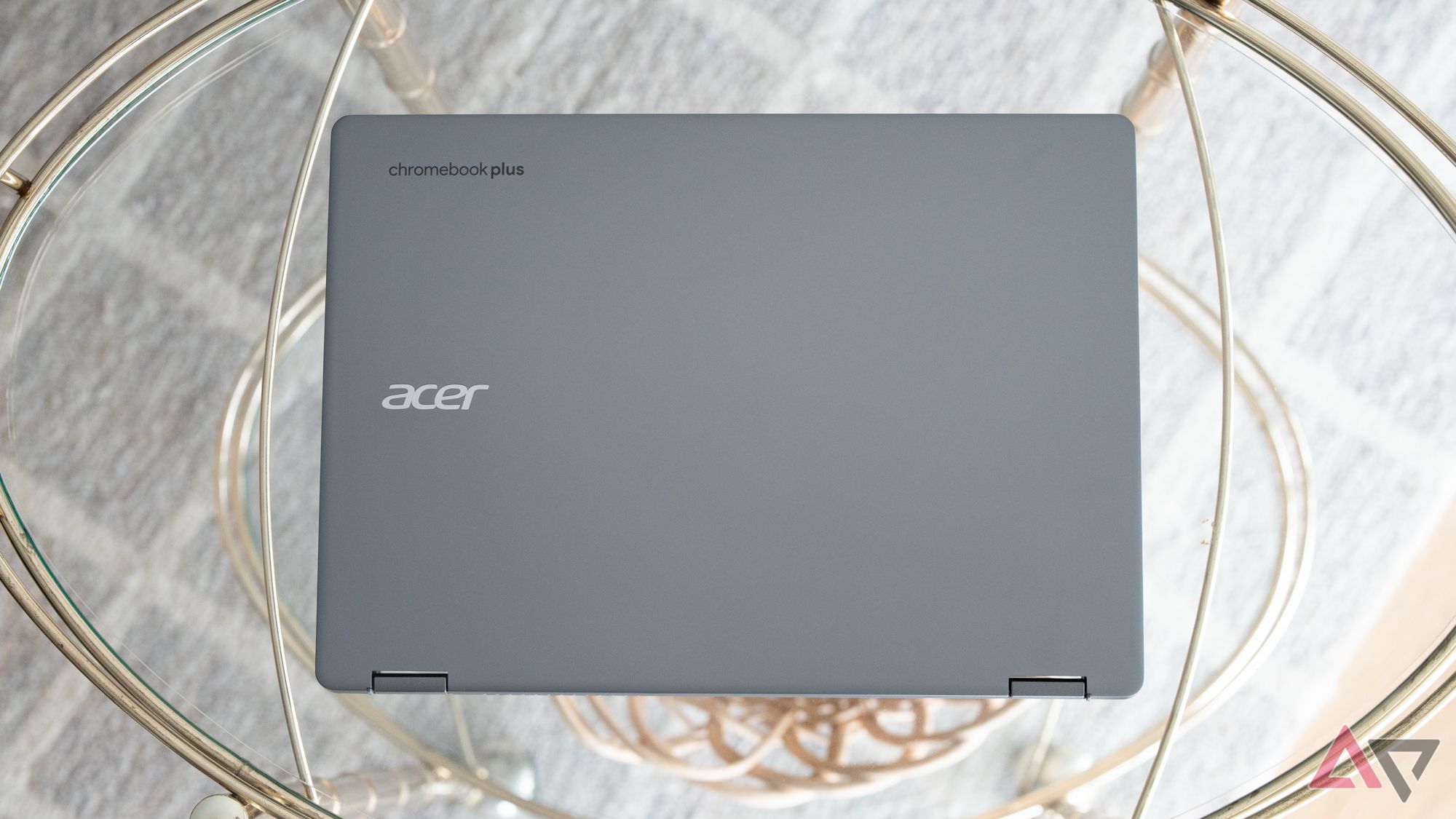 The back of a closed Acer Chromebook Plus Spin 514 lying on a glass table