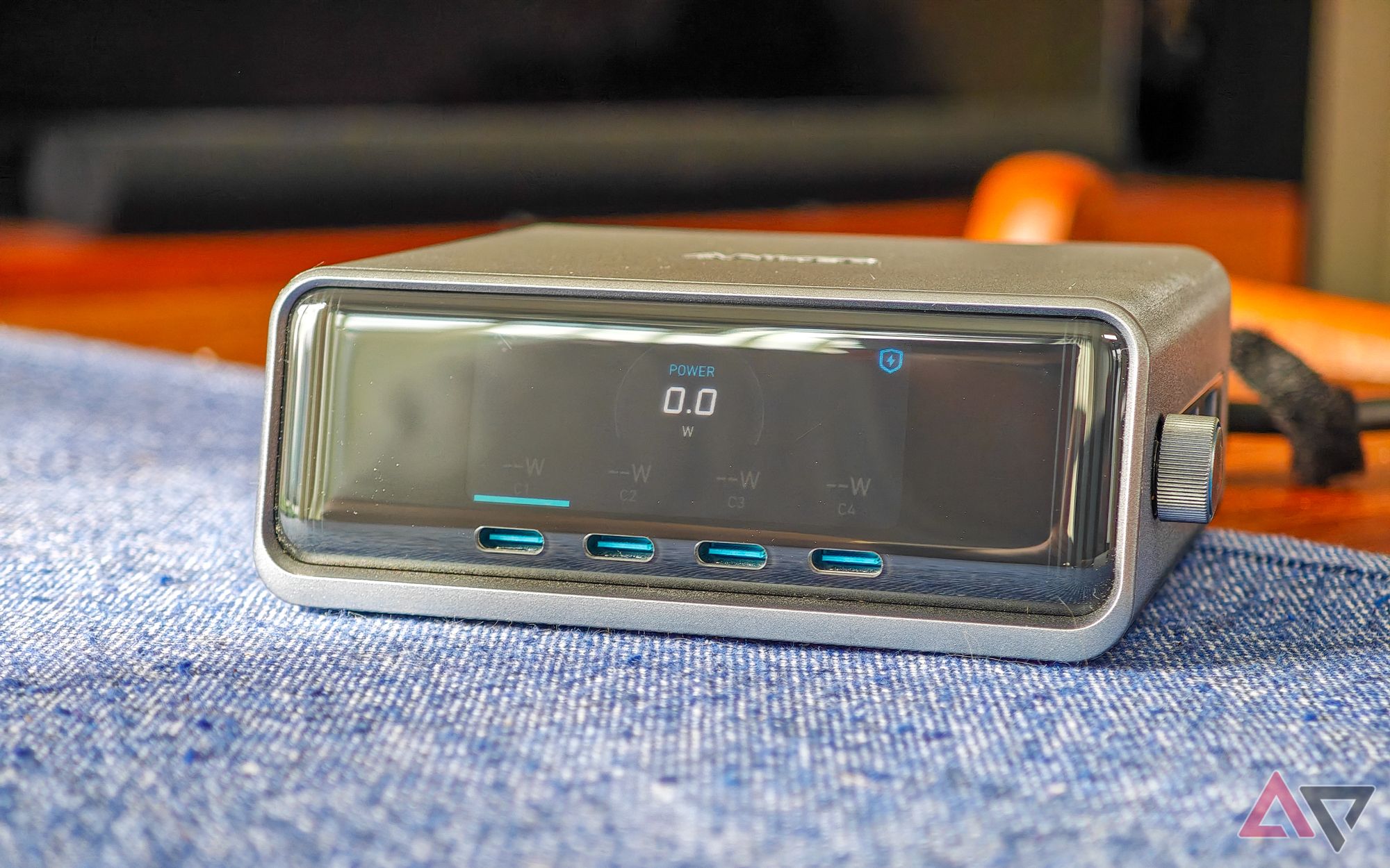 Anker Prime 250W desktop charger sitting on a blue cloth on a wooden table, seen from the front with nothing plugged in