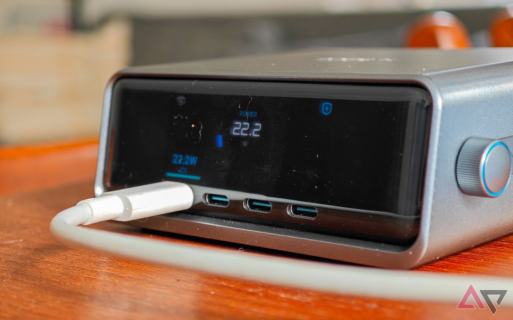 Anker Prime 250W desktop charger sitting on a wooden table with a white cable plugged into a USB-C port