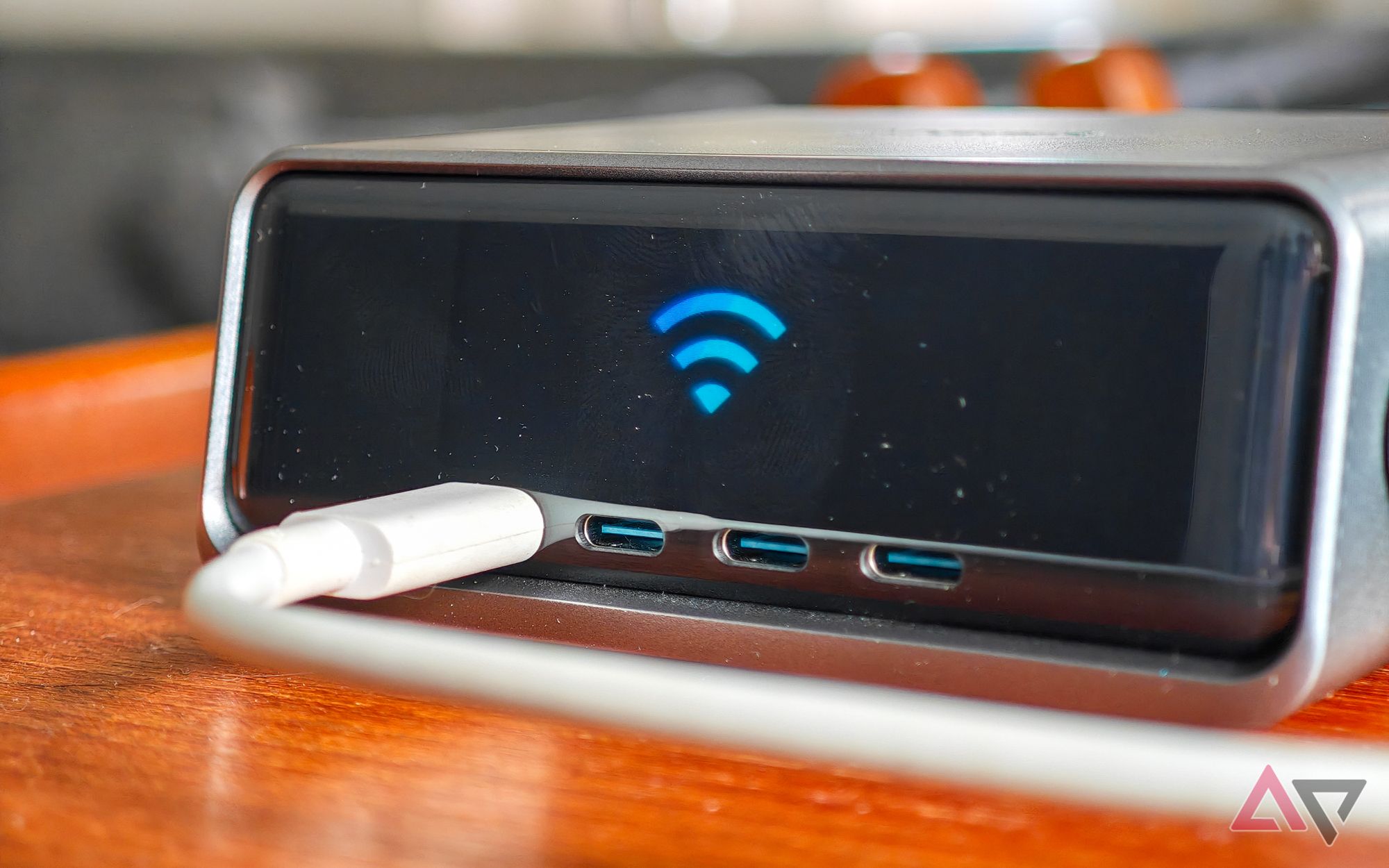 Anker Prime 250W desktop charger sitting on a wooden table, with a Wi-Fi logo on the screen
