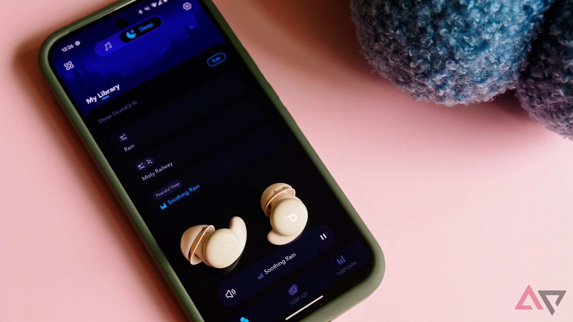 The Anker Soundcore Sleep A20 earbuds resting on a Pixel 9 Pro with the app open.