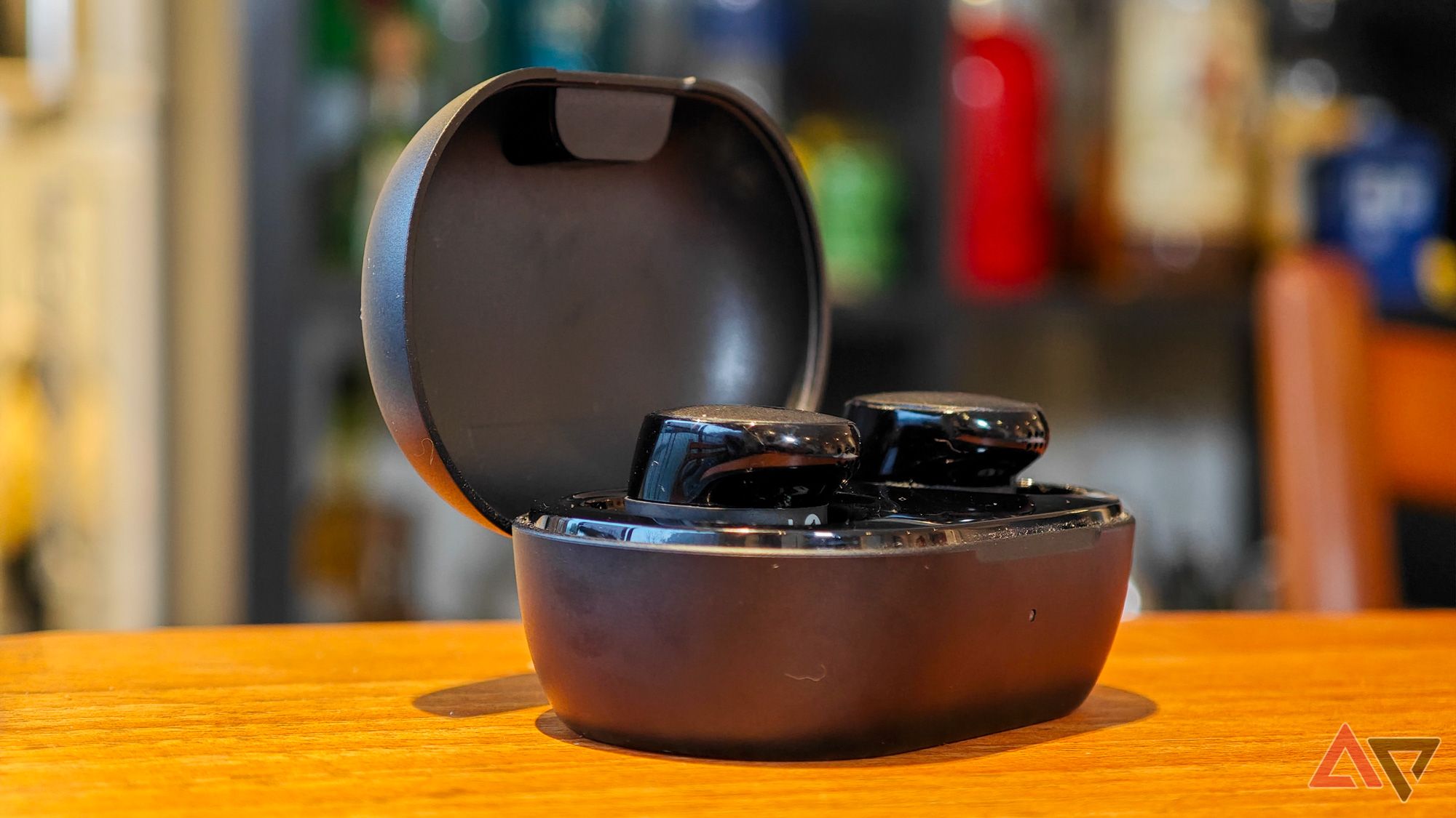 The case of the Bose QuietComfort Earbuds lay open on a wooden table