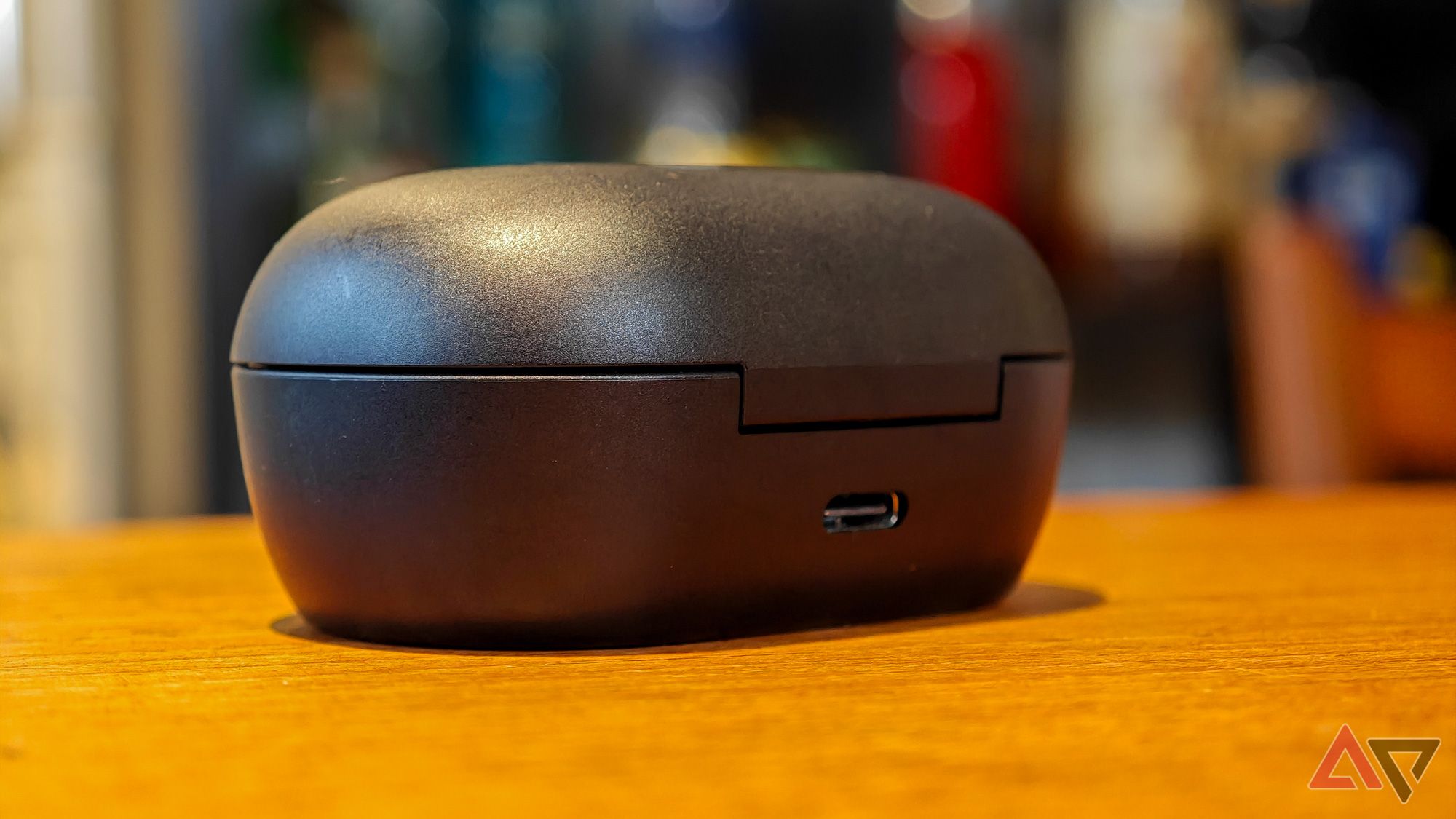 Bose QuietComfort Earbuds case on a wooden table featuring a USB-C port