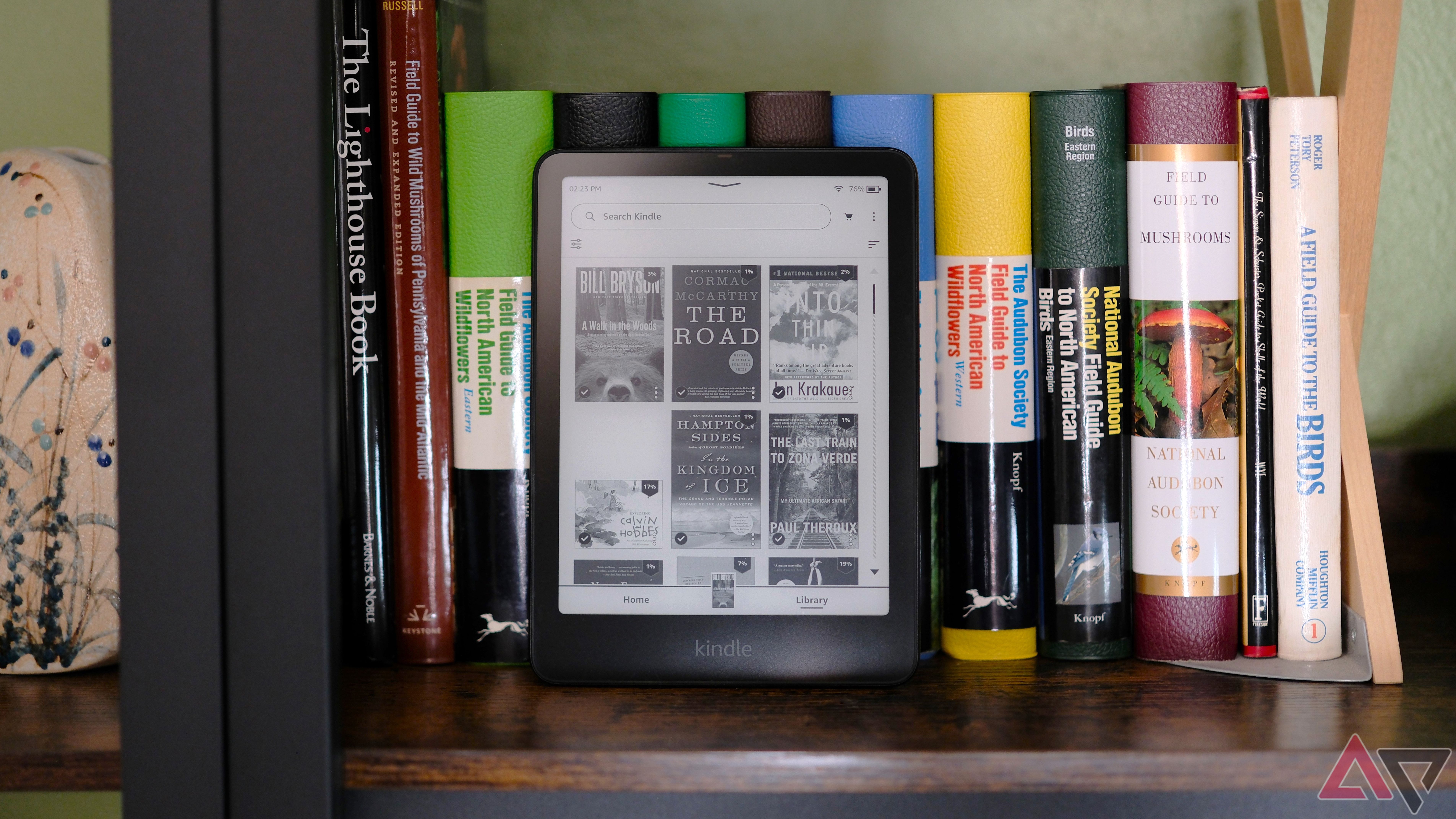 Kindle Paperwhite (2024) sitting on book shelf showing screen with library