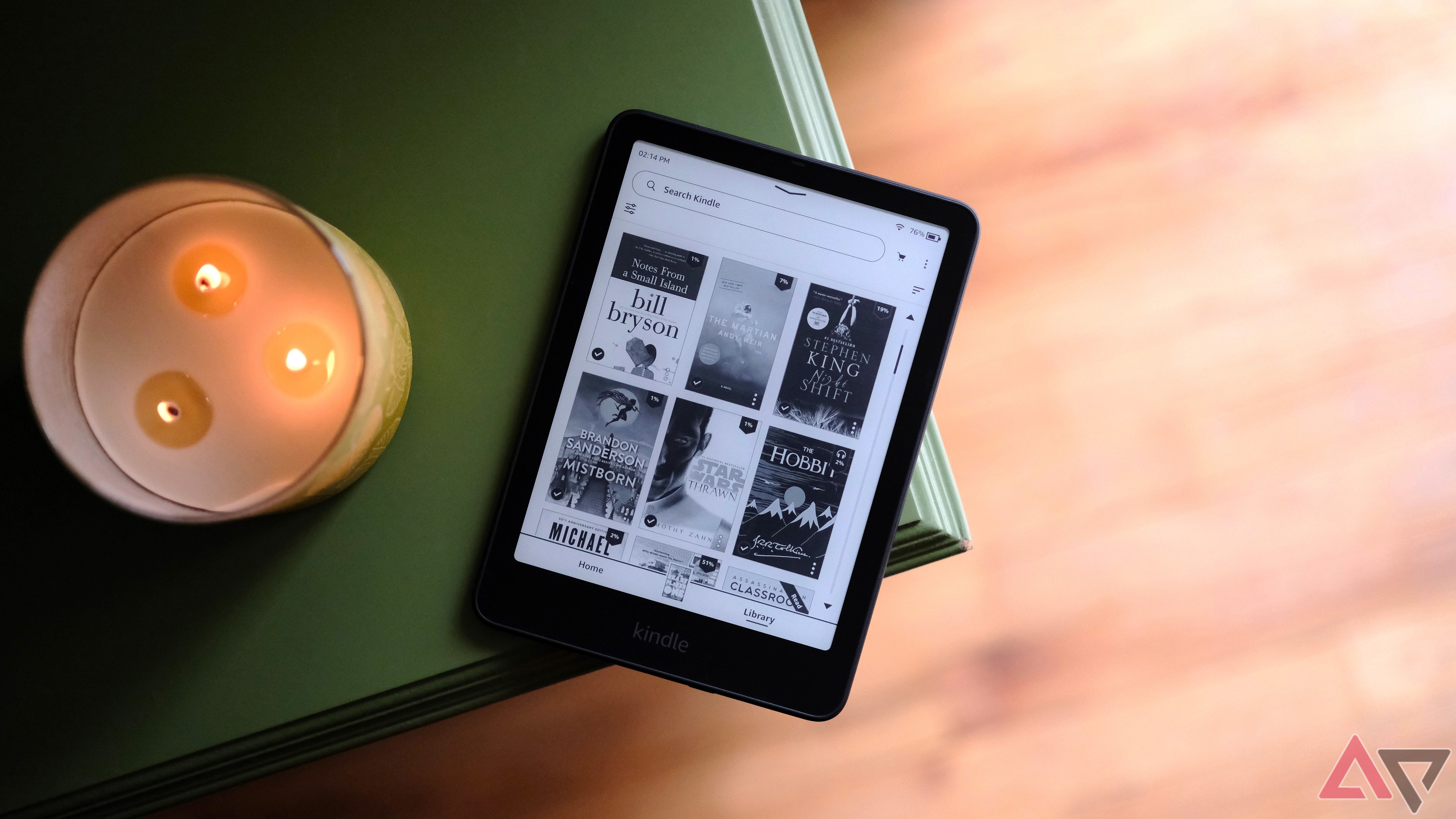 Kindle Paperwhite (2024) laying on edge of table showing screen with book selection