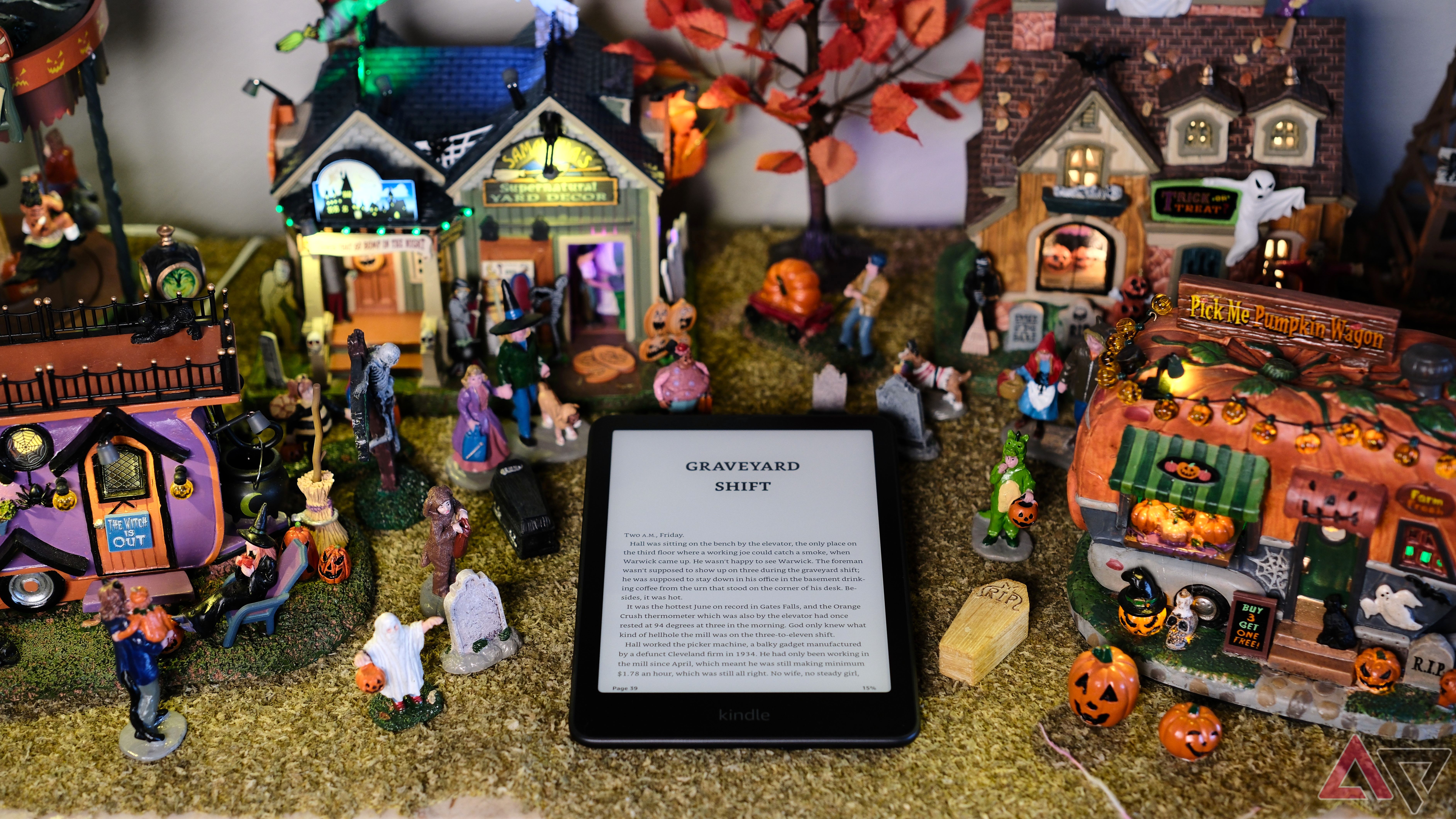 Kindle Paperwhite (2024) laying around halloween decorations with screen on reading graveyard shift