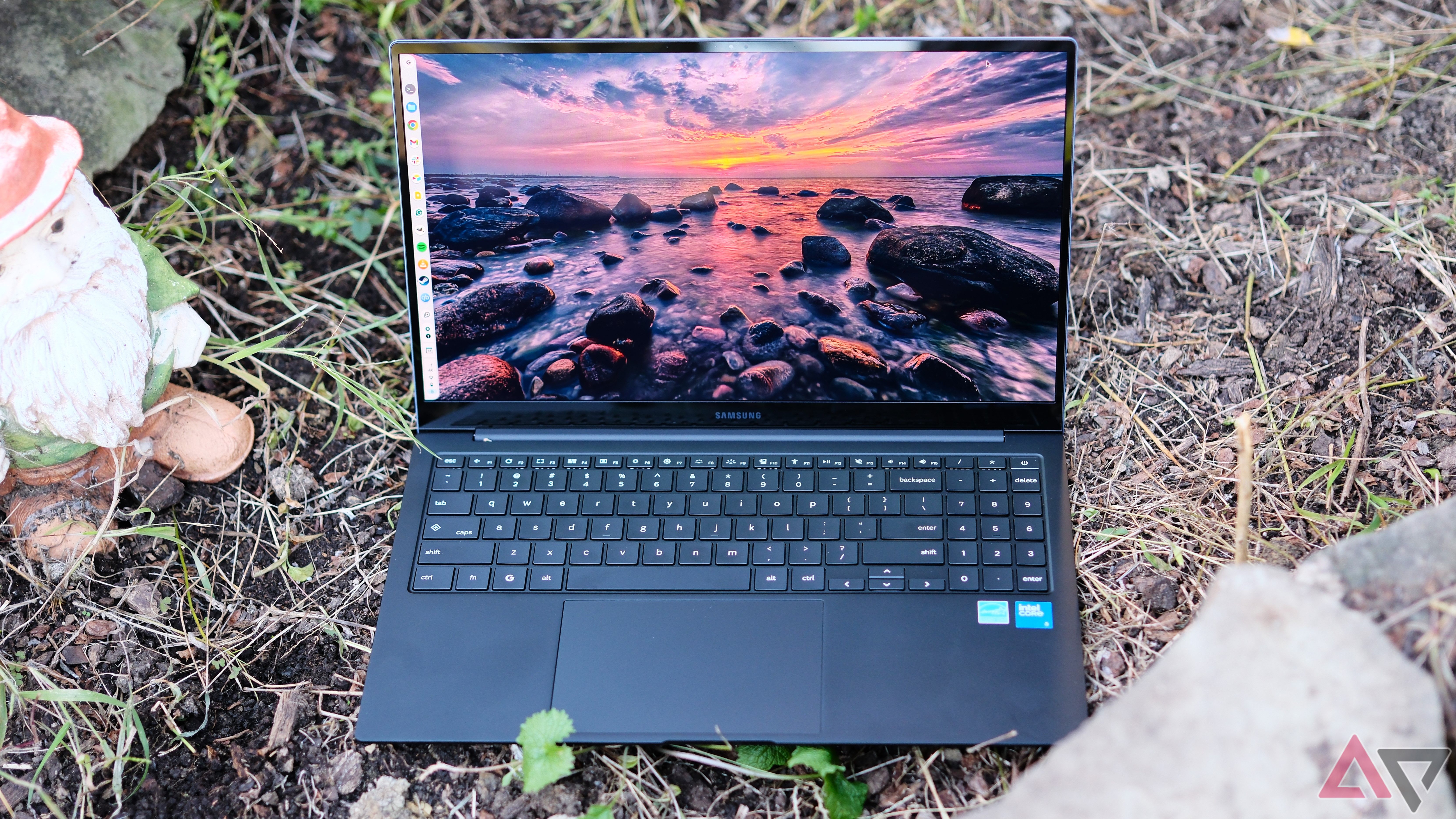 Samsung Chromebook Plus sitting on grass with lid open showing screen and keyboard