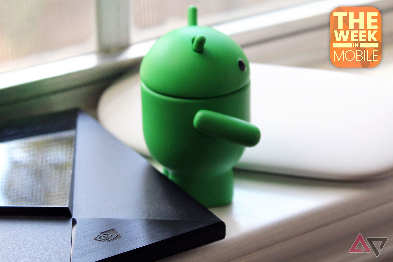 An Android bot figurine with its back turned to the Nvidia Shield TV, looking towards a Google TV Streamer.