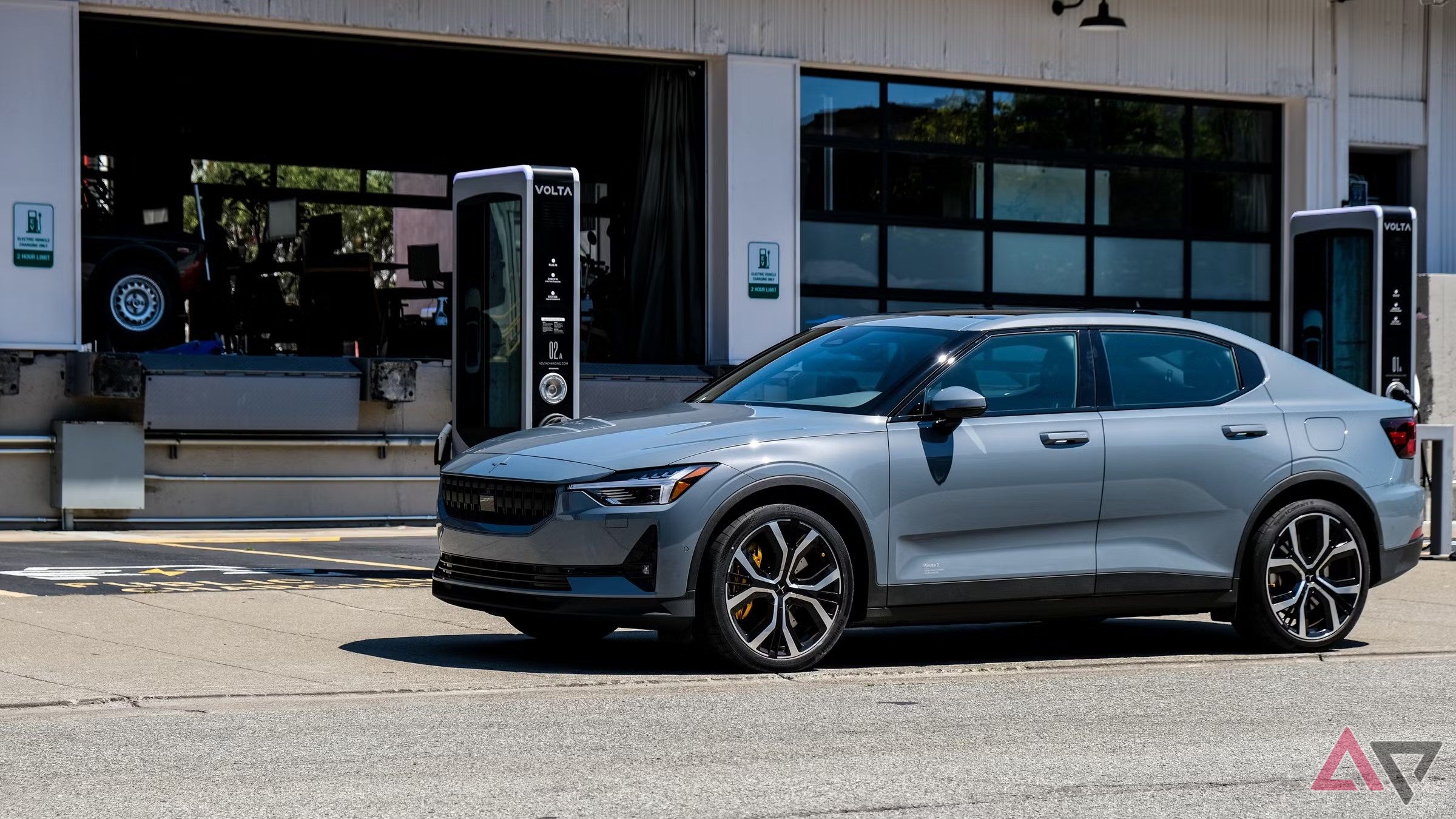 An electric vehicle parked outside a garage near a charging station