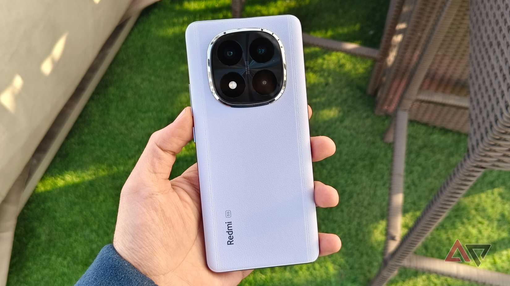 Redmi Note 14 Pro Plus leather-like back texture in front of chair and green grass