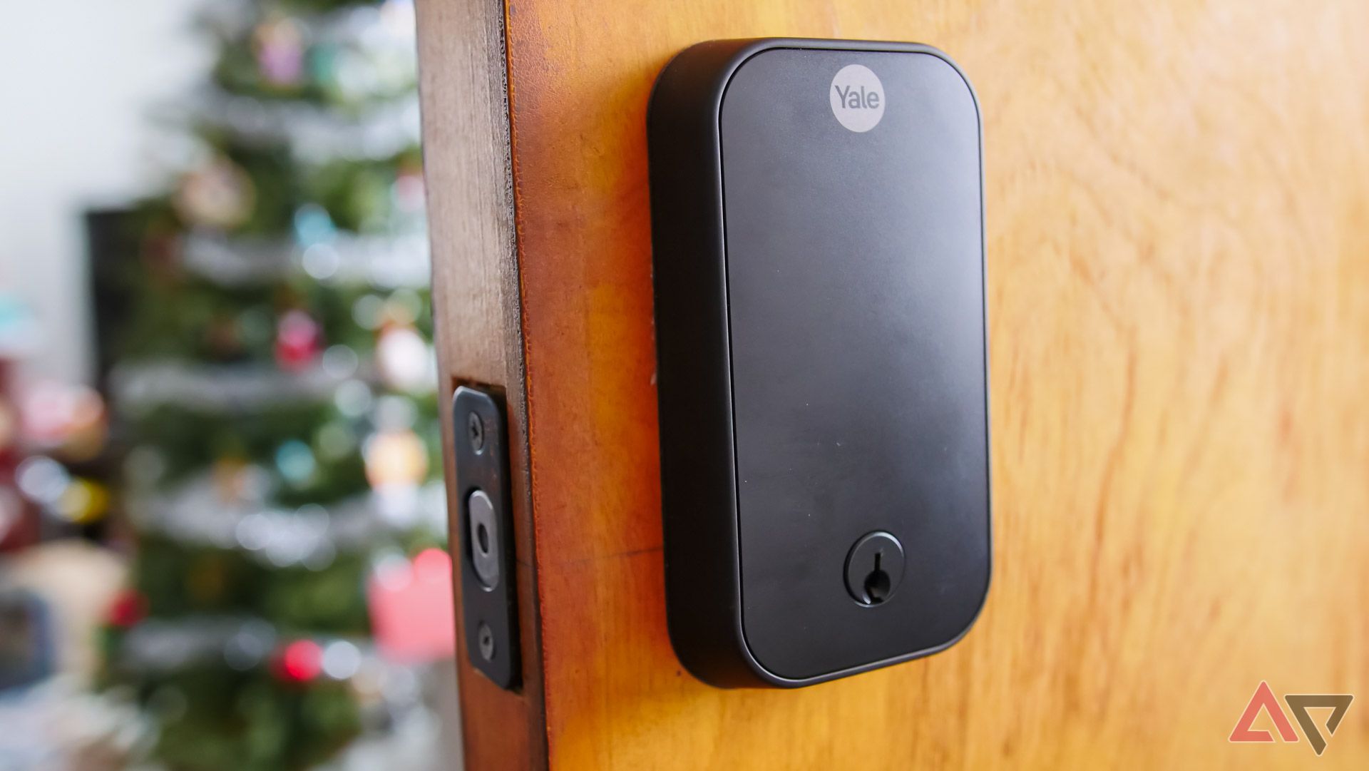 A smart lock embedded within a door with a Christmas tree in the background.