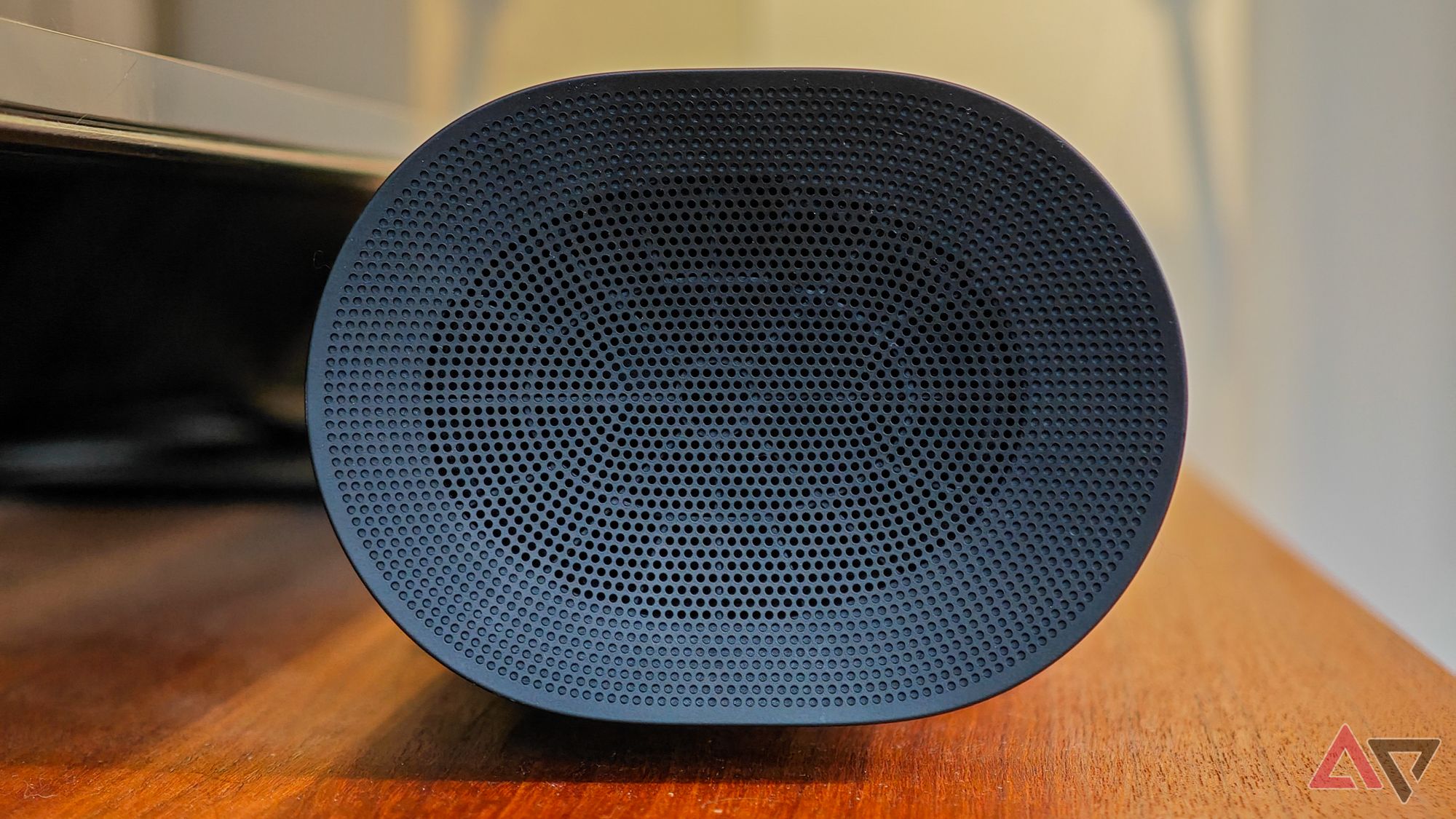 Black Sonos Arc Ultra soundbar resting on a teak wooden cabinet, photographed from the side