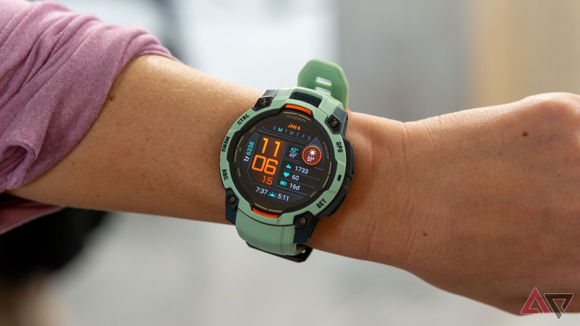 A green smartwatch reading 11:06 on a woman's wrist.