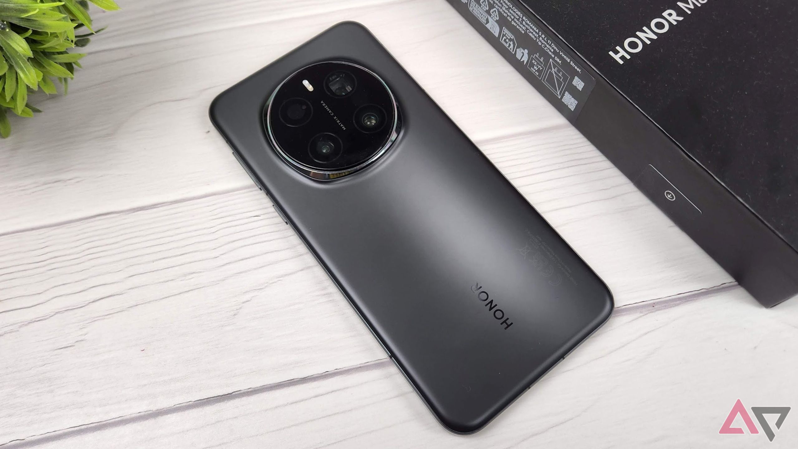 Honor Magic 7 Pro face down on a wooden table next to a plant and a black box