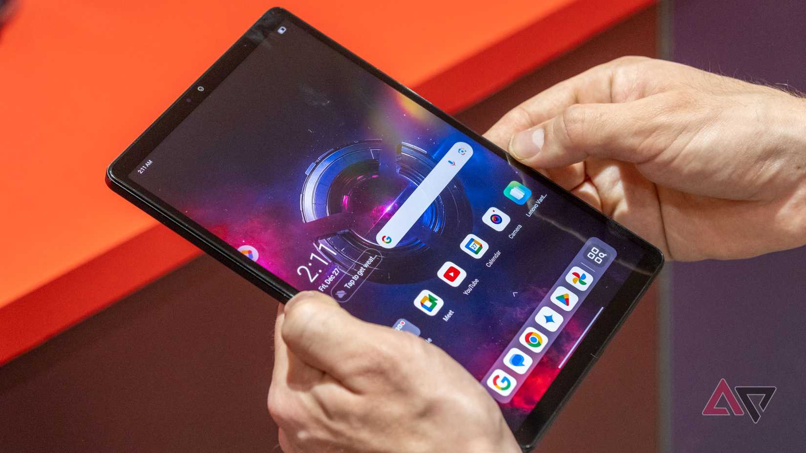 Hands holding a small Android tablet with its screen on.