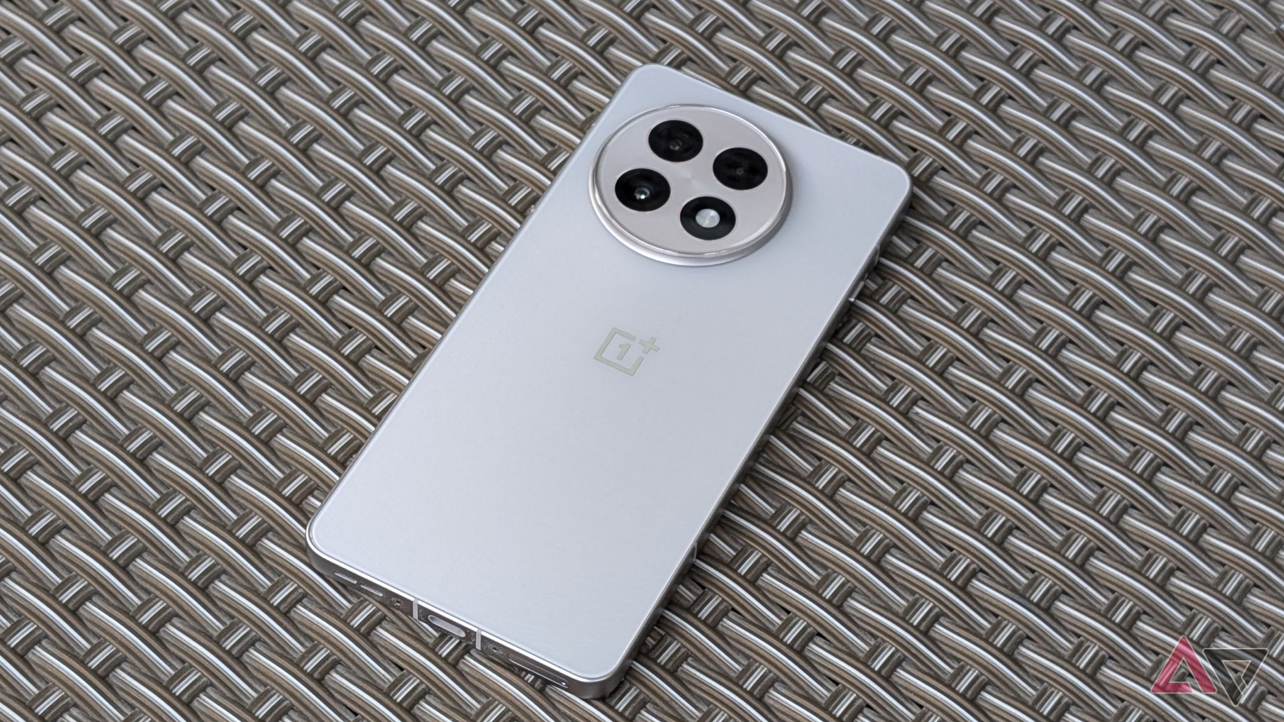 OnePlus 13R in silver finish resting on textured woven surface