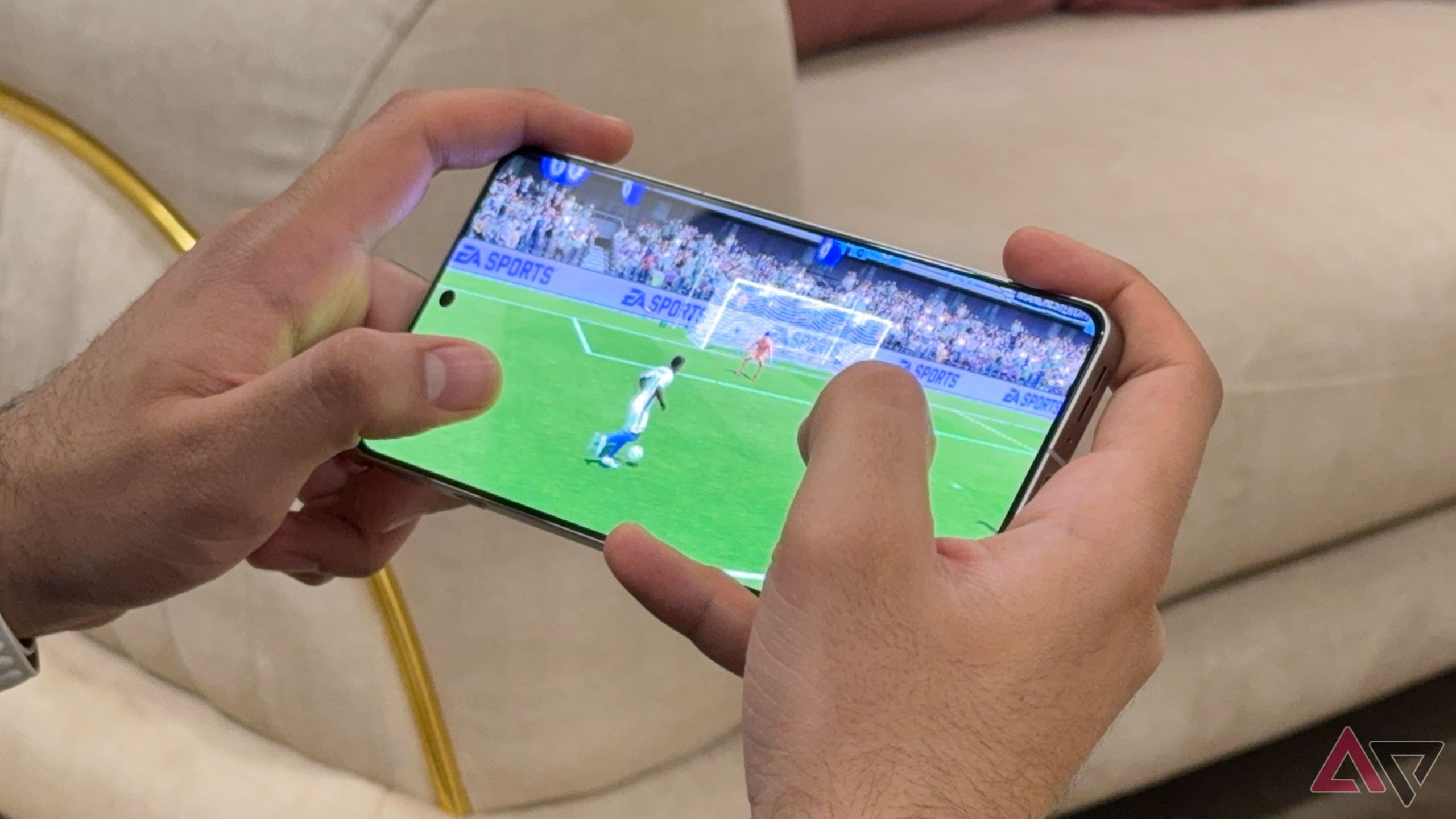 OnePlus 13R displaying soccer game, hands gripping phone tightly