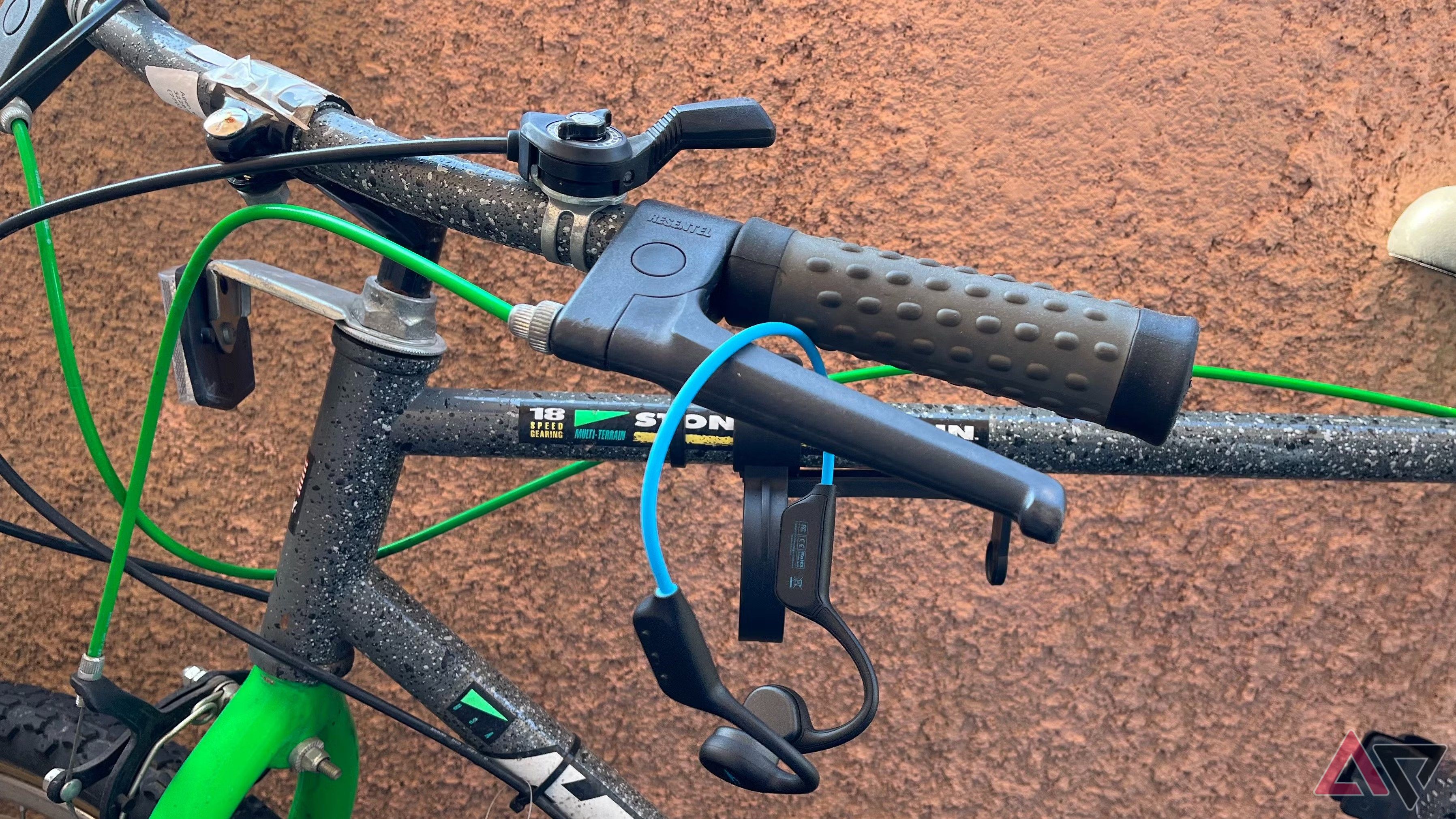 A blue pair of headphones hanging from a bike handlebar.