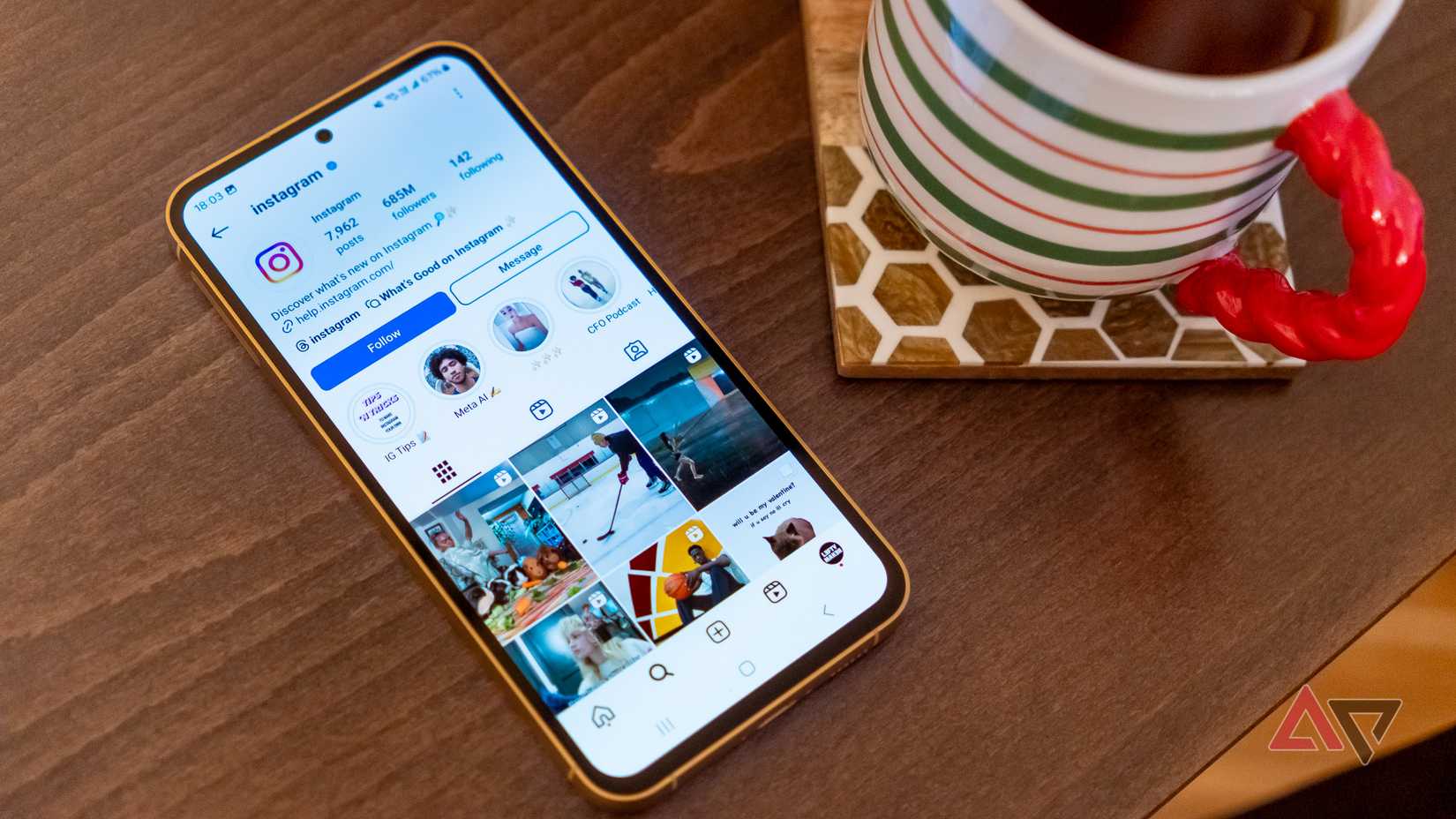 a phone displaying the instagram page for instagram on a wooden table next to a cup of tea