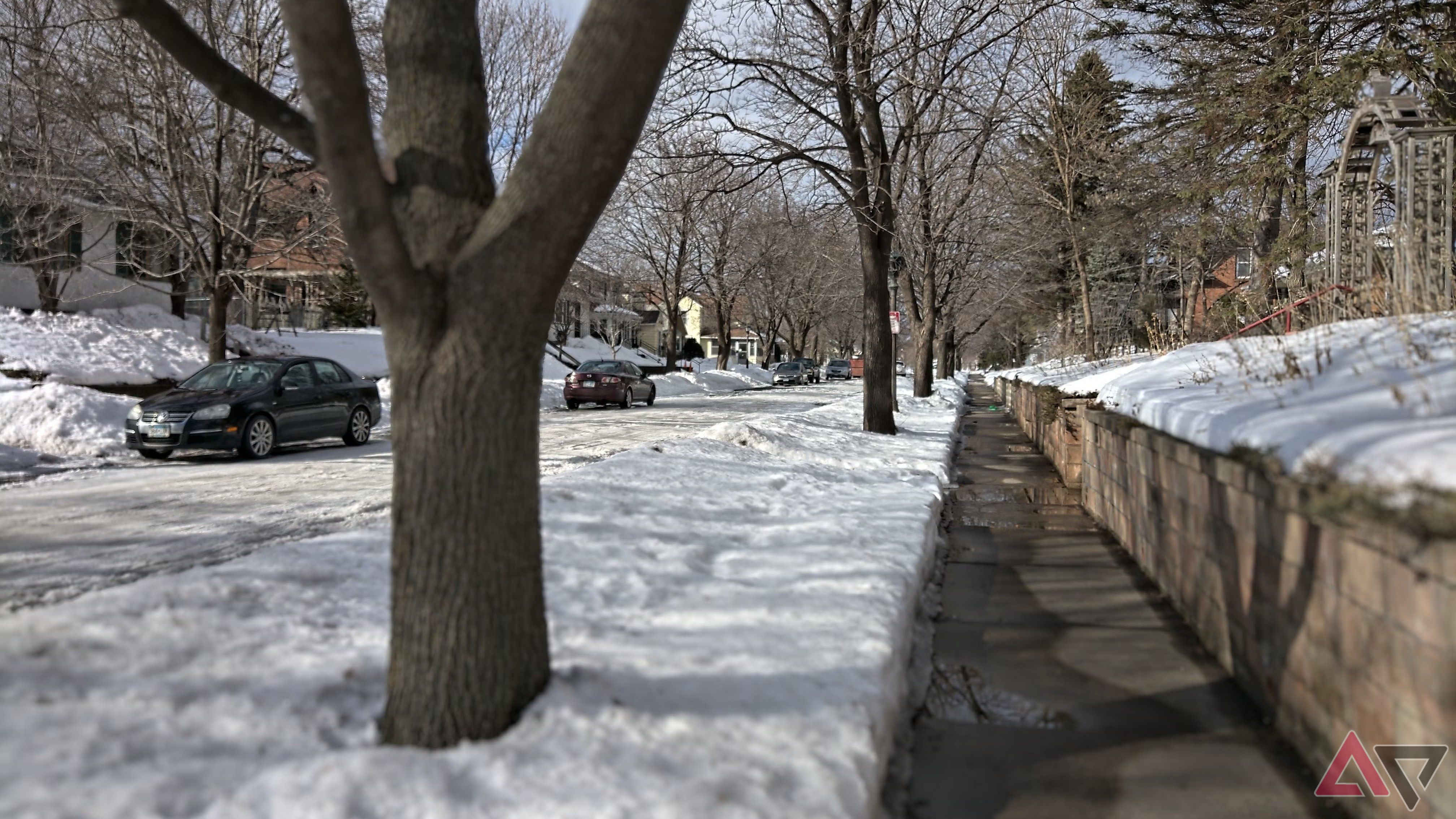 A shoveled sidewalk in a snow-covered street scene.