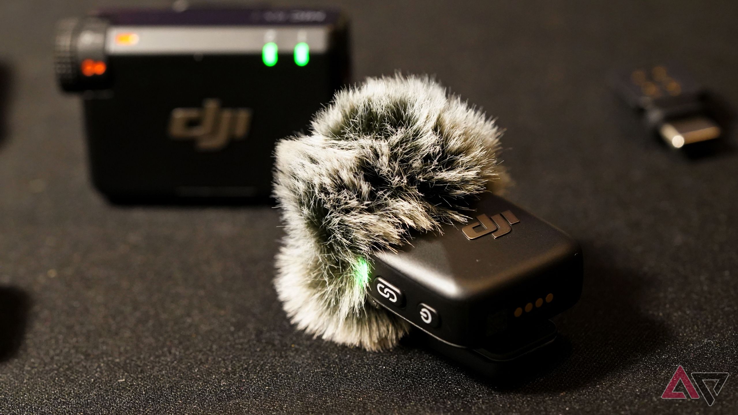 DJI Mic Mini transmitter and receiver combo with a deadcat attached, against a black mat