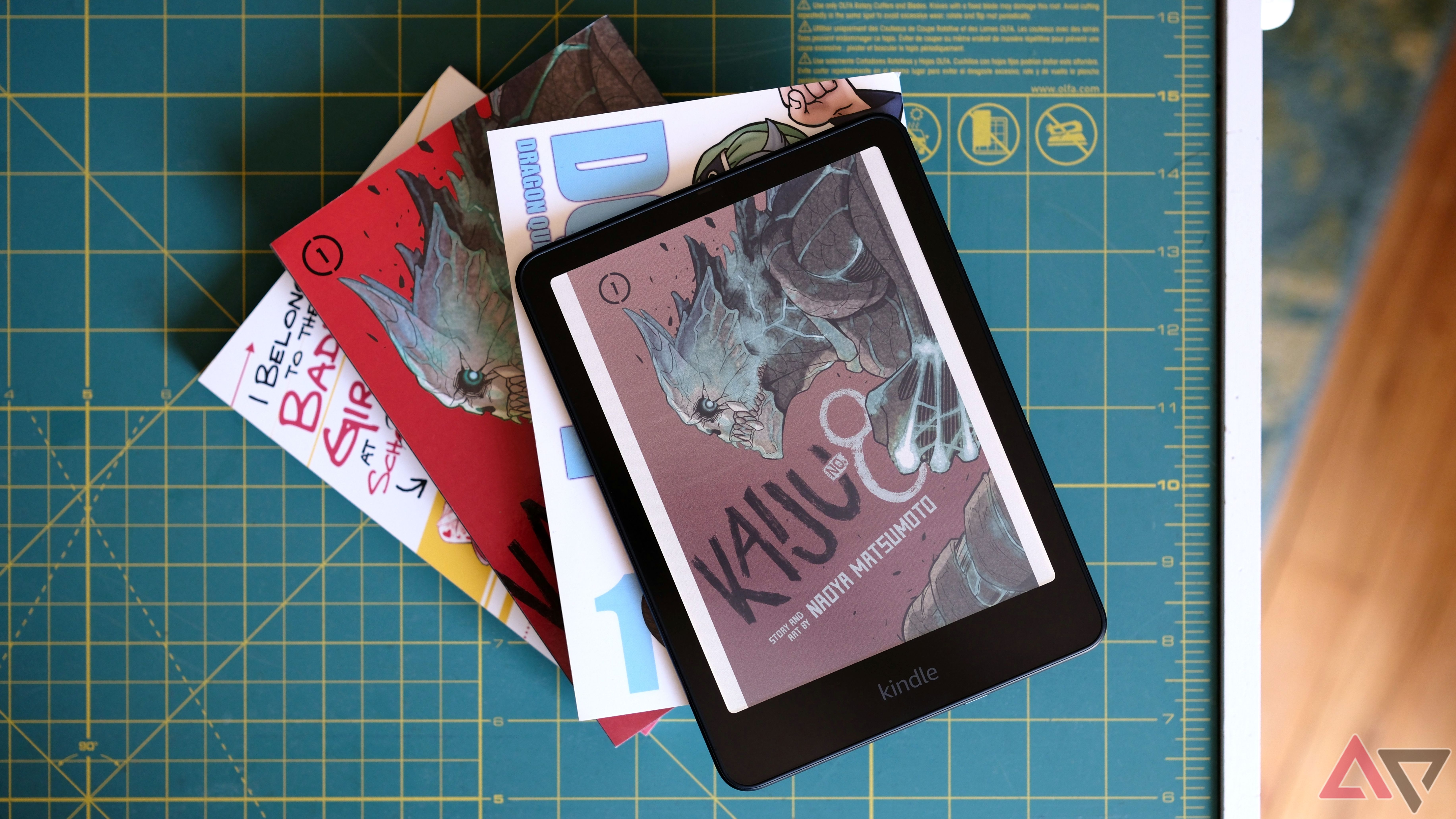 Kindle Colorsoft sitting on top of stack of manga