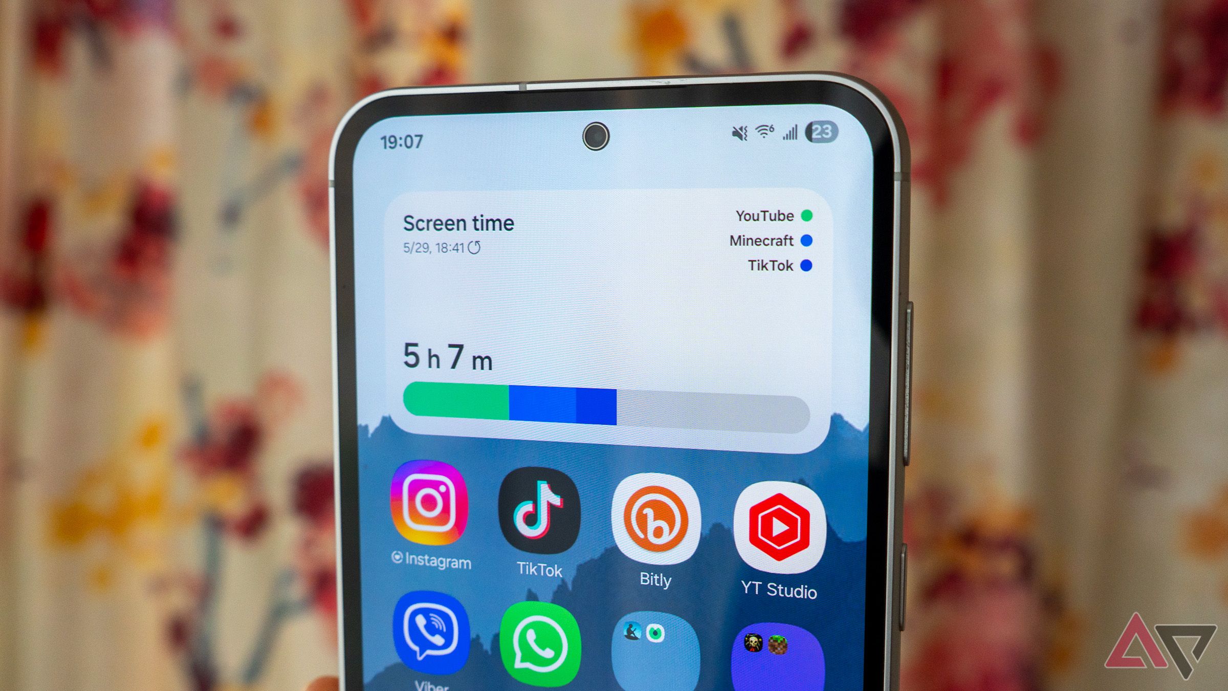 a close-up of a samsung phone home screen with a digital wellbeing screen time widget shown