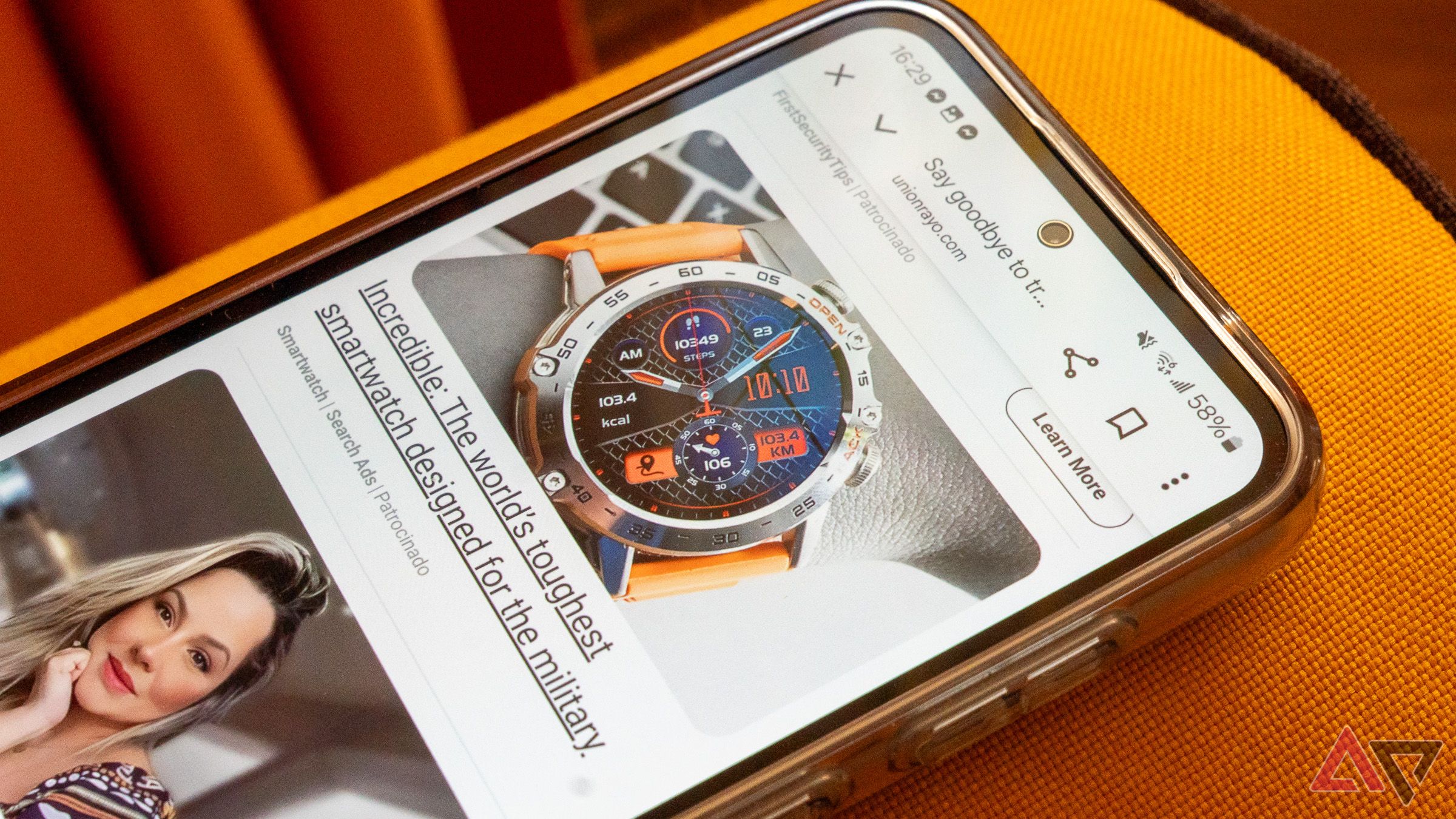 a closeup of a phone displaying an ad for a watch resting on an orange couch
