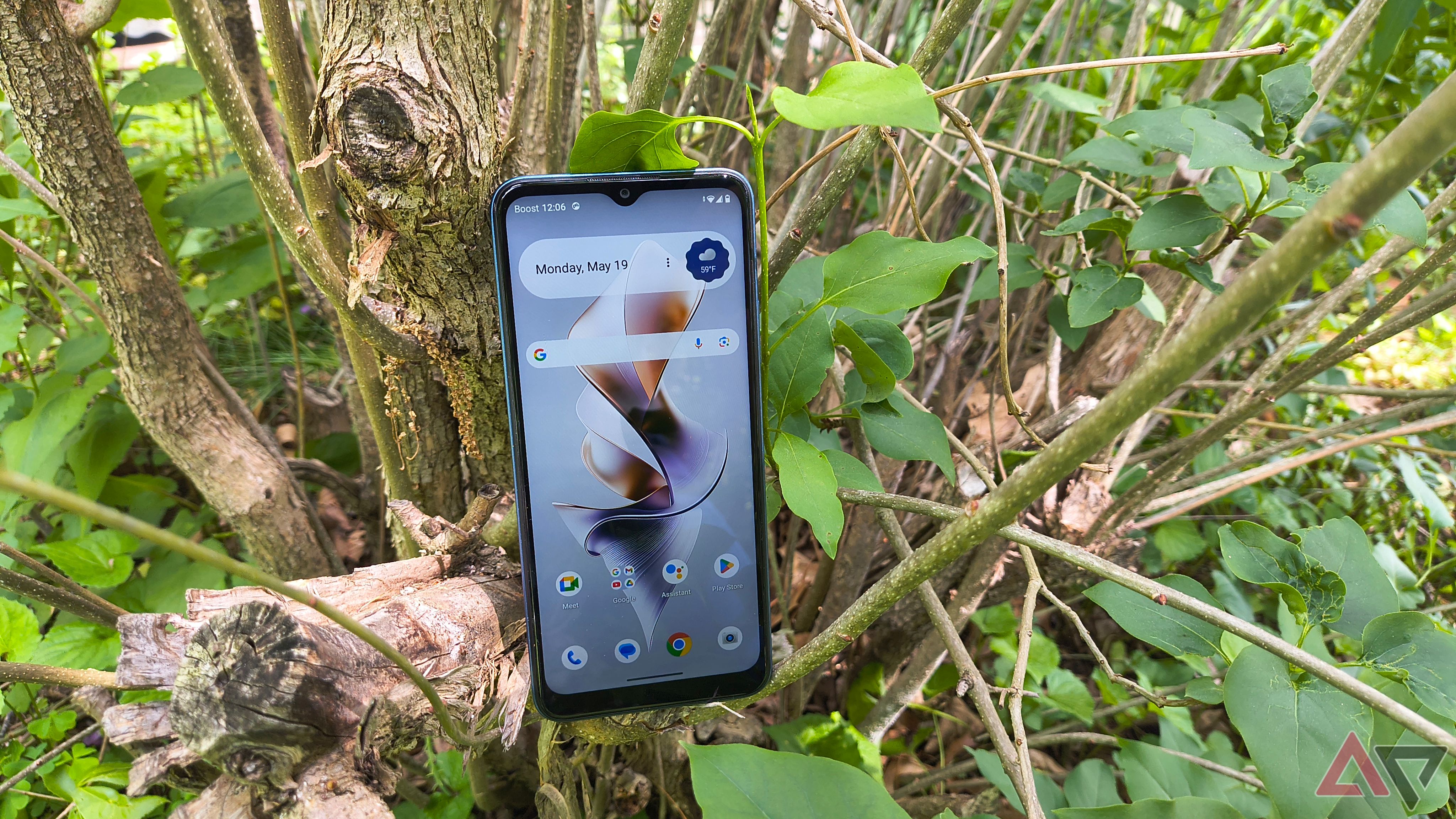 A Boost Summit 5G sitting in a bush with the home screen visible
