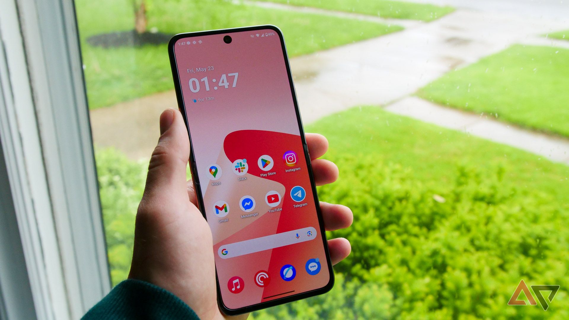 The Moto Razr Ultra held in a hand next to a window.