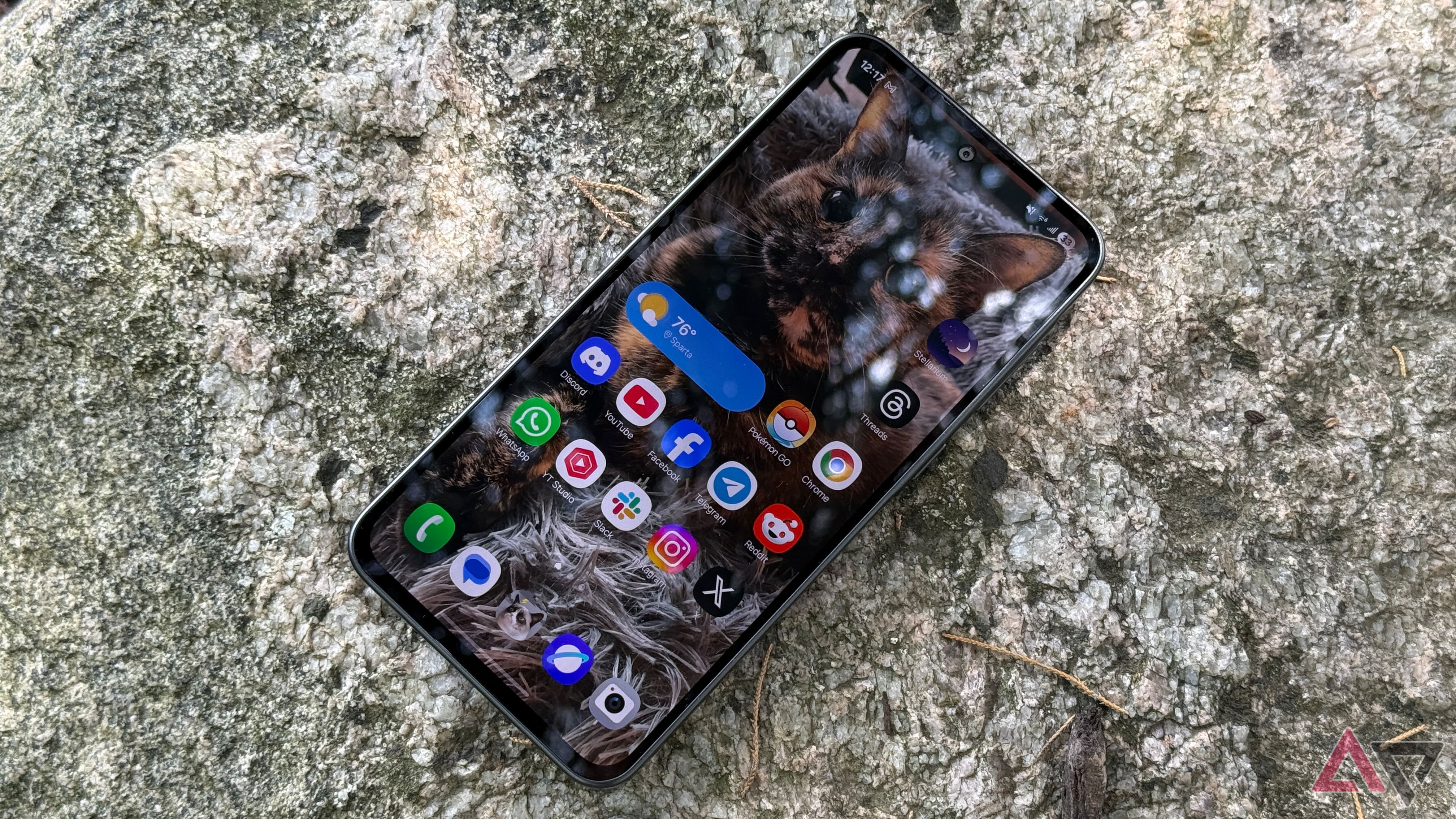 Samsung Galaxy A36 home screen while sitting on a rock