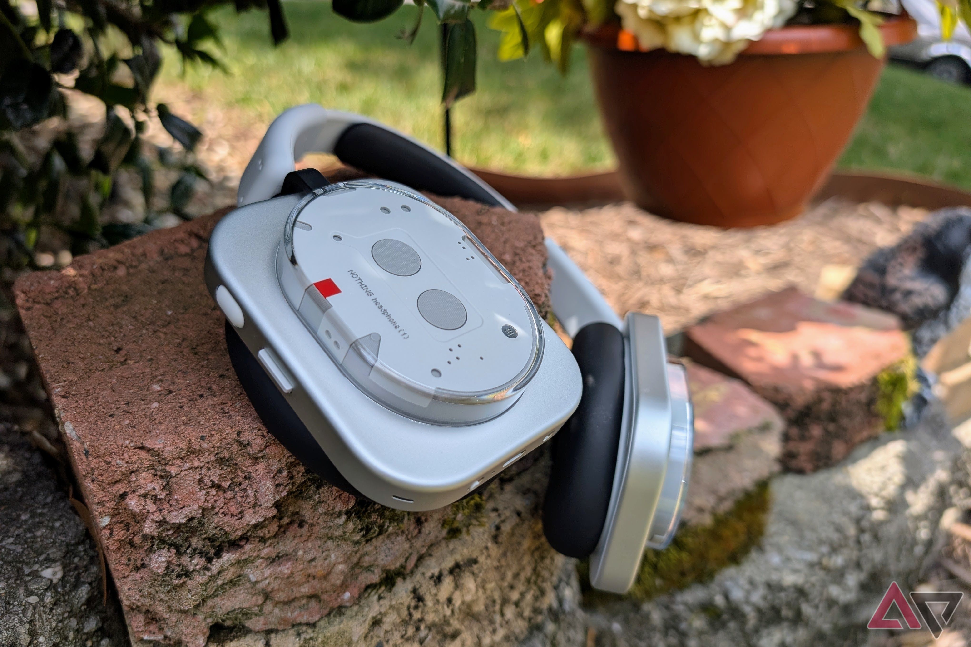 Nothing Headphones (1) on a brick wall with flowers in background