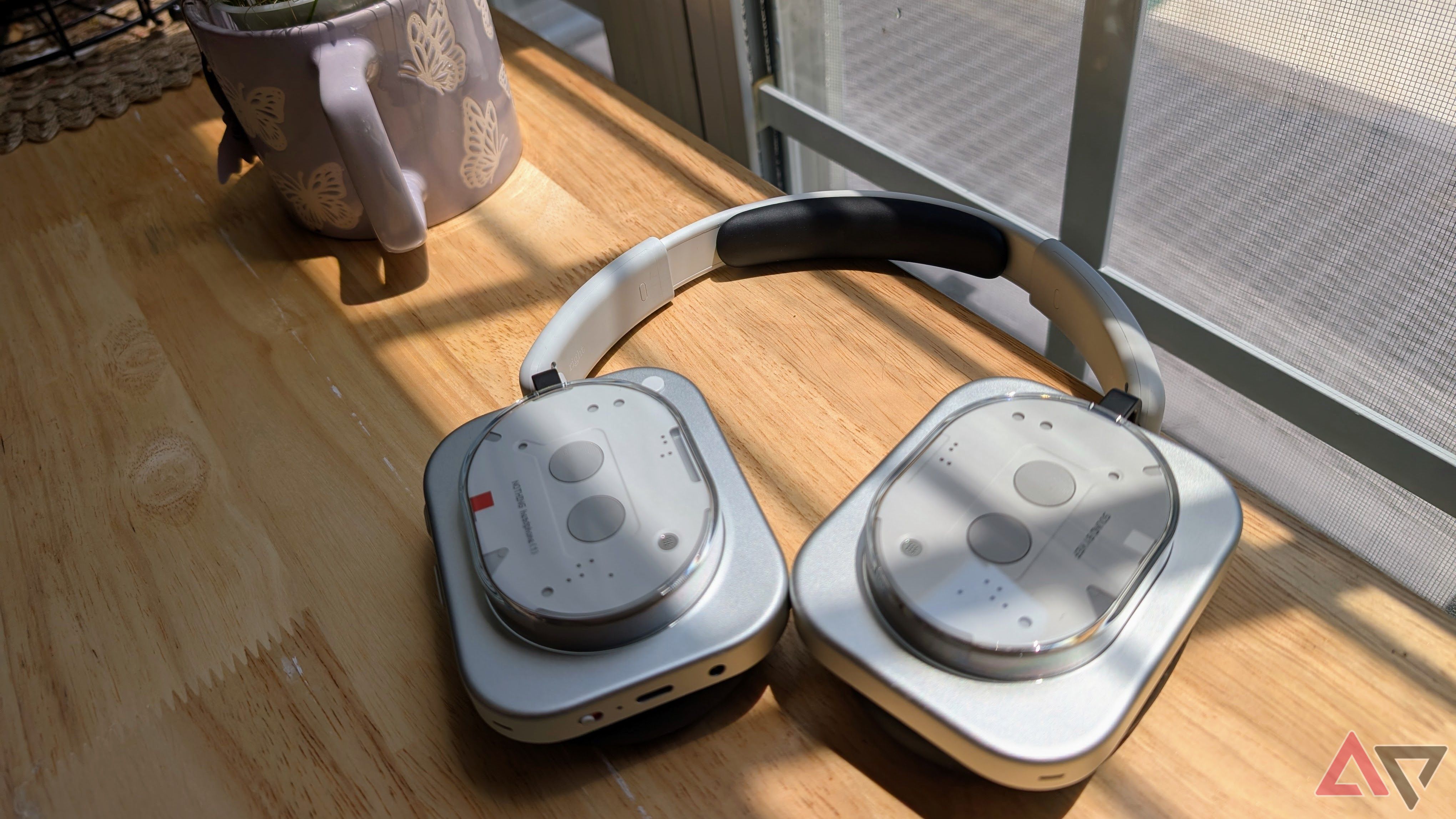 Nothing Headphones (1) on wooden counter next to plant