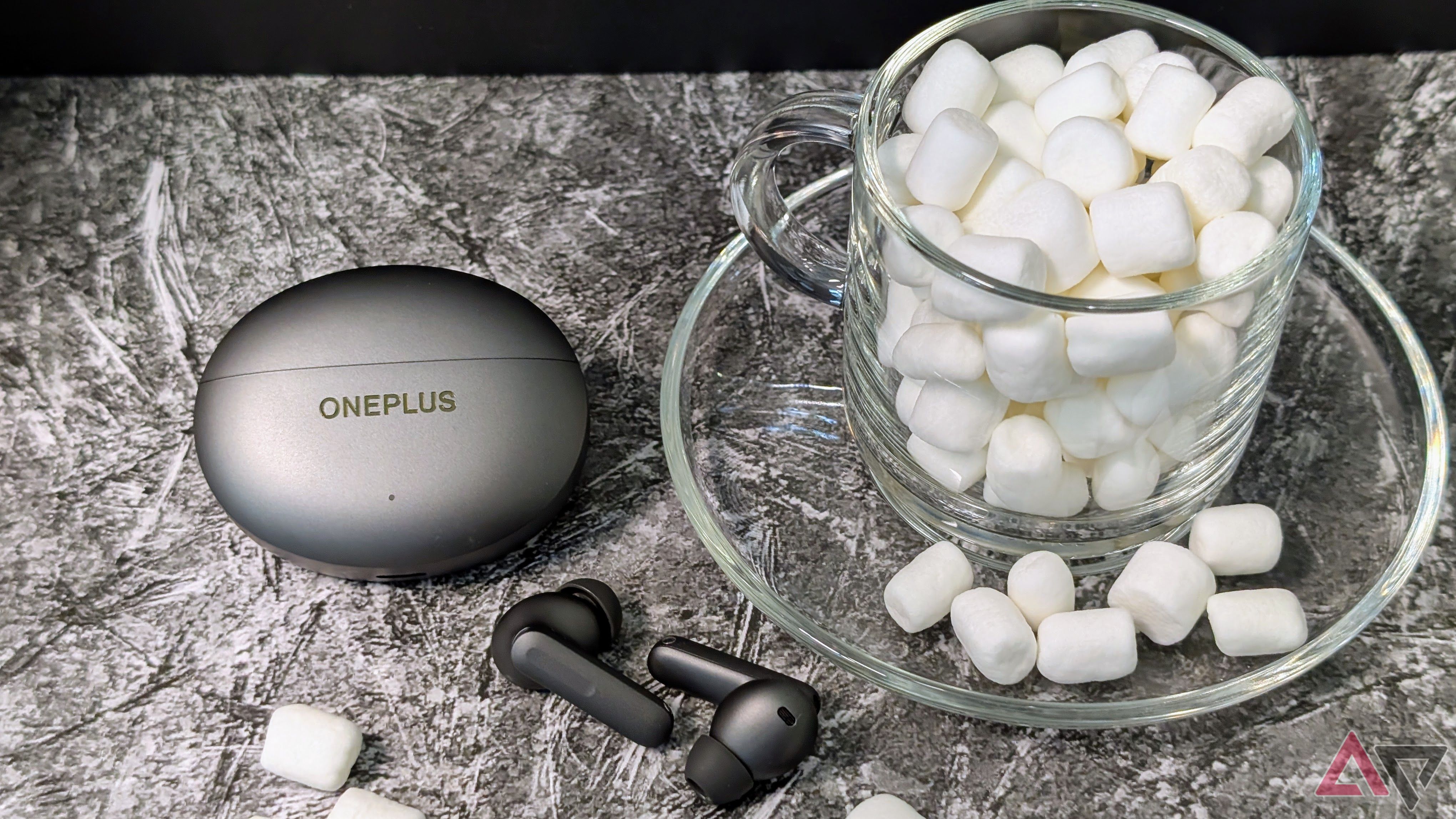 OnePlus Buds 4 case and earbuds next to a cup of marshmallows